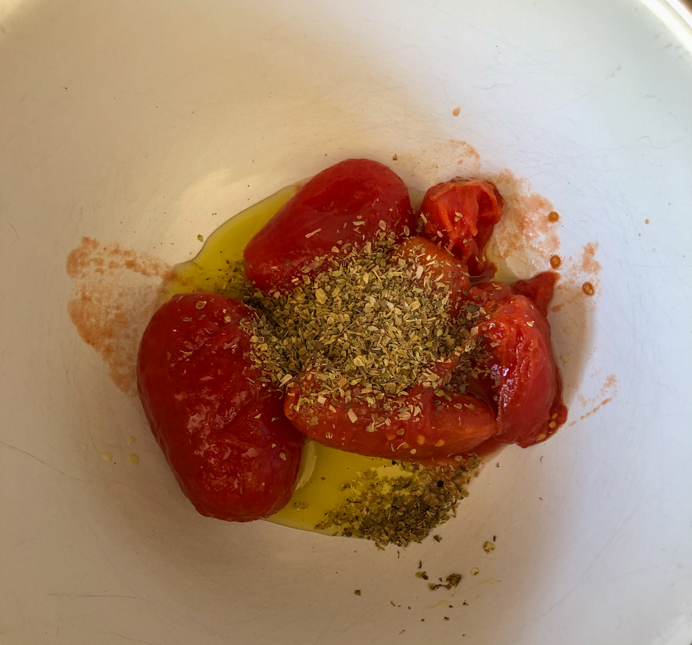 Tomatoes, oil and oregano in a bowl