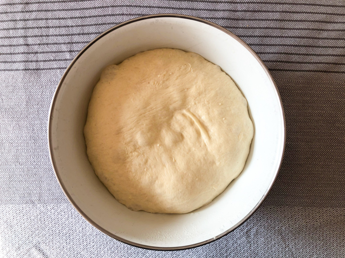 Pizza dough proving in a bowl.